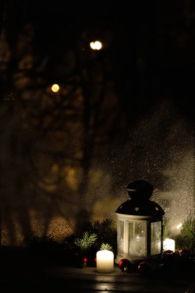 Lanterna de Natal com queda de neve, velas, vista da janela na rua da noite — Fotografia de Stock