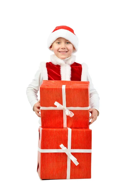 Adorable boy in santa clothes peeks out behind Christmas big gift boxs. Isolated white background. — Stock Photo, Image