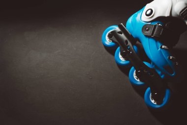 Koyu renkli grunge backgroung üzerinde mavi tekerlekli paten inline paten veya paten görünümünü kapat