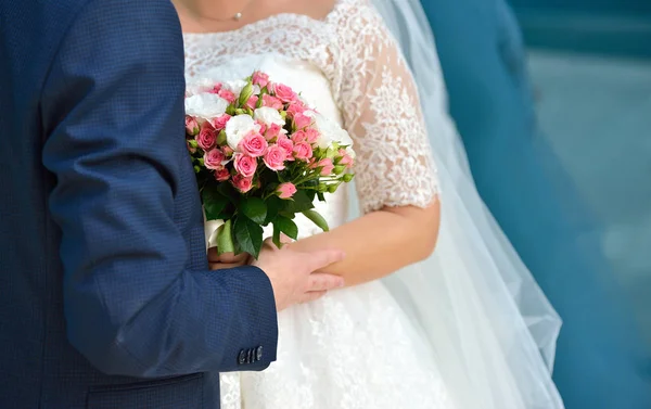 Pasangan pengantin memegang karangan bunga merah muda dan mawar putih di latar belakang biru — Stok Foto