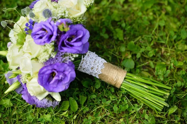 Close-up of wedding bouquet with white and purple flowers on green grass — Stock Photo, Image