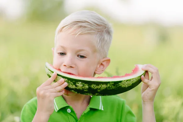 Caucasian little boy with blond hairs eating fresh watermelon in summer garden, outdoors. — Stock Photo, Image