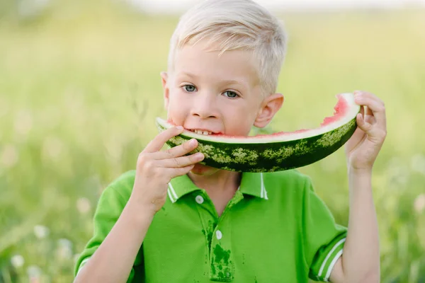 Lindo niño pequeño con pelos rubios comiendo sandía en el jardín de verano — Foto de Stock
