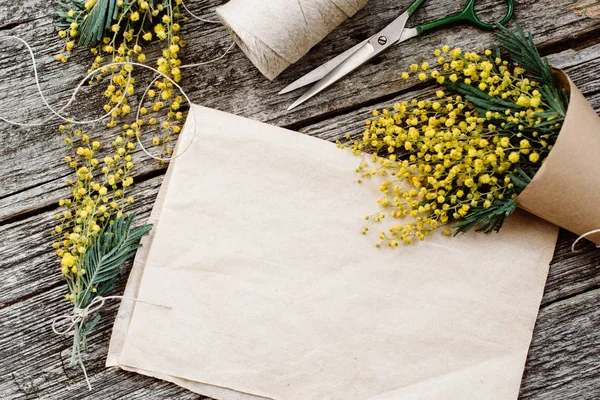 Ramo de mimosa. vendajes torzal y tijeras sobre mesa de madera rústica, papel viejo para texto — Foto de Stock