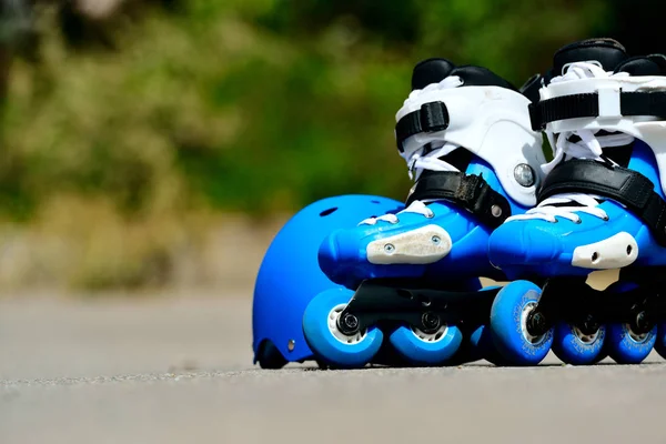 Kolečkové inline brusle s přilbou v skate parku na pozadí šedé asfalt — Stock fotografie