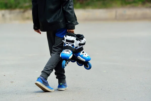 Menino lindo com patins nas mãos — Fotografia de Stock