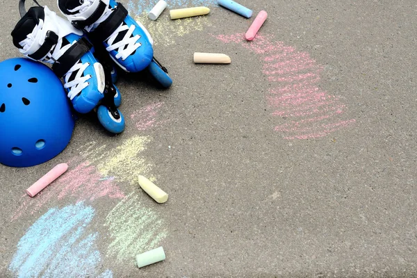 Kolečkové inline brusle s přilbou v skate parku na šedé asfaltu maloval barevné pozadí — Stock fotografie