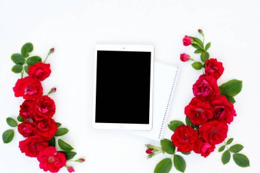 Çerçeve çiçek tablet ile kırmızı yat ve bej çiçek tomurcukları beyaz zemin üzerine yükseldi..