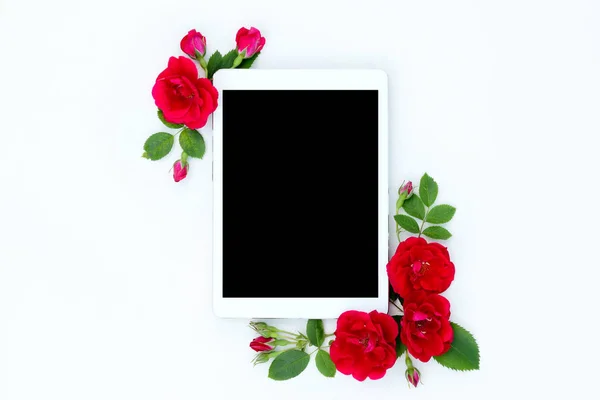 Çerçeve çiçek tablet ile kırmızı yat ve bej çiçek tomurcukları beyaz zemin üzerine yükseldi..