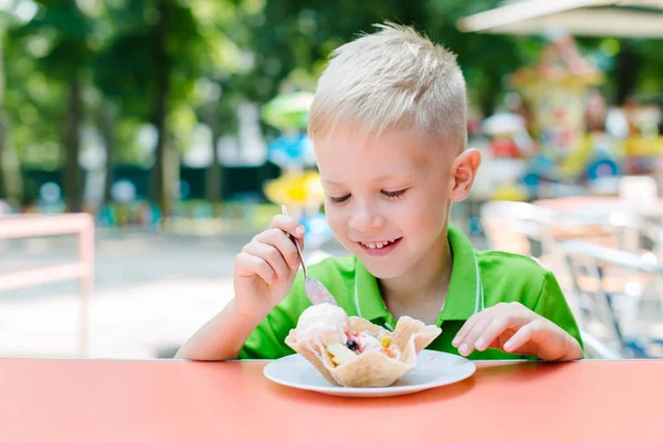 Feliz chico divertido lindo está comiendo helado en la cafetería — Foto de Stock