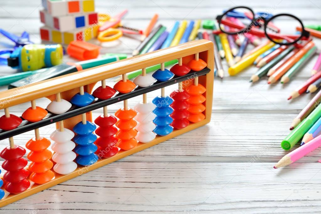 Close up view of abacus scores mental arithmetic with colorful back to school supplies over white table. Space for text.