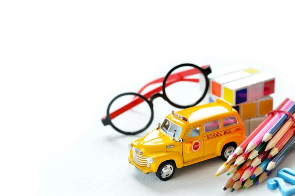 Vista de cerca del colorido autobús amarillo de vuelta al borde de los suministros escolares sobre la mesa blanca. Espacio para texto . — Foto de Stock