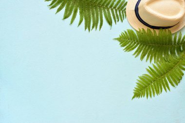 Yaz tatili, tatil yeri teması. Yeşil palmiye yaprakları ile mavi arka plan üzerinde beyaz kova şapka. Düz yatıyordu