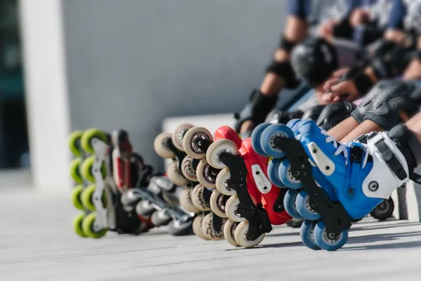 Ноги роликових міхурів, які носять вбудовані роликові ковзани, сидять у парку на відкритому повітрі, крупним планом вигляд на колеса для катання — стокове фото