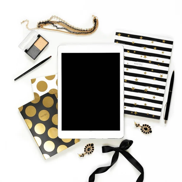 Düz yatıyordu moda kadınsı ev ofis çalışma alanıyla tablet, şık siyah altın notebook, kozmetik ve beyaz arka plan üzerinde takı. Kadın iş çalışma masası üzerinde Üstten Görünüm