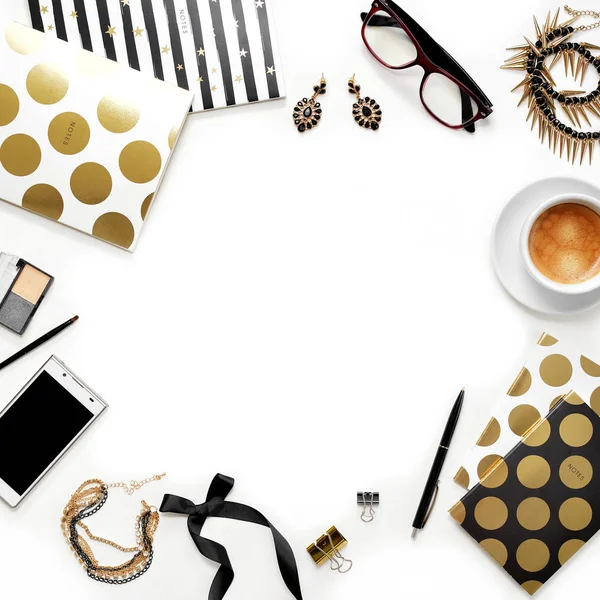 Düz yatıyordu moda kadınsı ev ofis çalışma alanı ile telefon, fincan kahve, şık siyah altın notebook, kozmetik ve beyaz arka plan üzerinde takı. Kadın iş çalışma masası üzerinde Üstten Görünüm