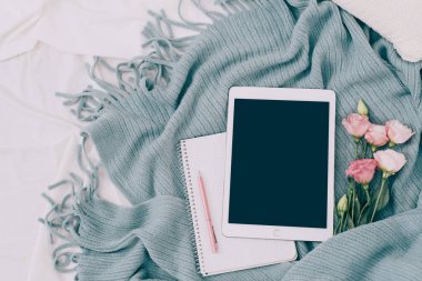 Tonda düz tablet ve çiçekler üzerinde beyaz battaniye ile turkuaz ekose yatıyordu