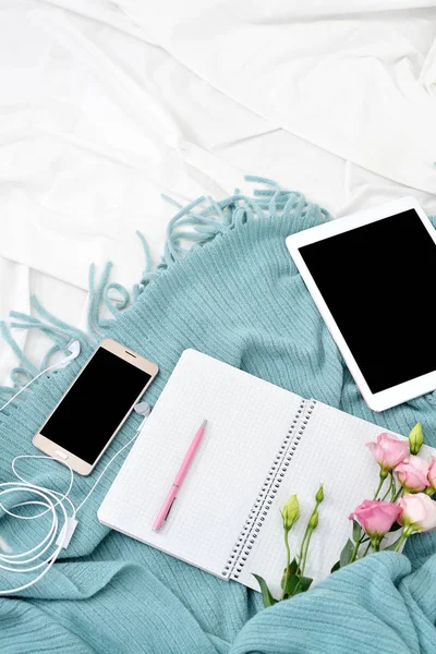 Tableta plana vertical, teléfono, taza de café y flores en manta blanca con cuadros de turquesa —  Fotos de Stock
