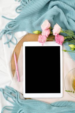 Dikey düz tablet ve çiçekler üzerinde beyaz battaniye ile turkuaz ekose yatıyordu