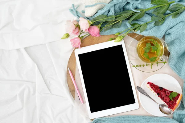 Ahududu cheesecake, nane çayı ve açık not defteri, tablet ile yatakta düz yatıyordu Kahvaltı