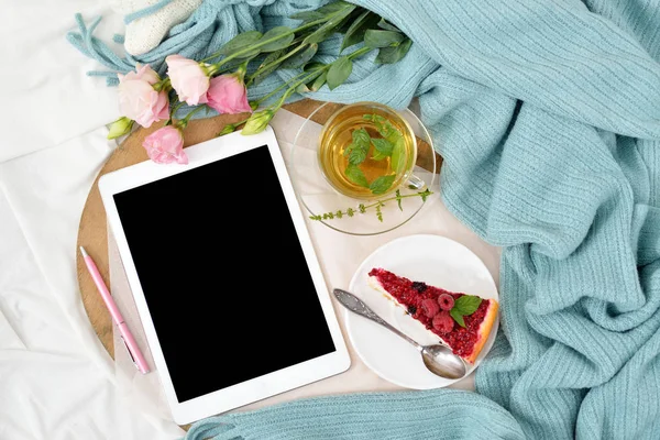 Ahududu cheesecake, nane çayı ve açık not defteri, tablet ile yatakta düz yatıyordu Kahvaltı