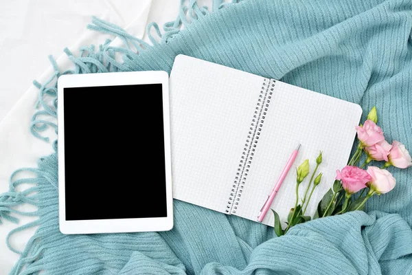 Плаский планшет, телефон, чашка кави та квіти на білій ковдрі з бірюзовою плед — стокове фото