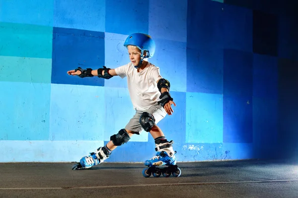 Молодий хлопчик на роликових ковзанах робить слайд на синій графіті стіни — стокове фото