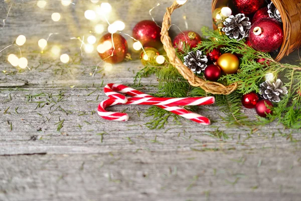 Christmas Basket with Vintage Gifts and Shining lights. Red balls, Pine cones on Wooden Table