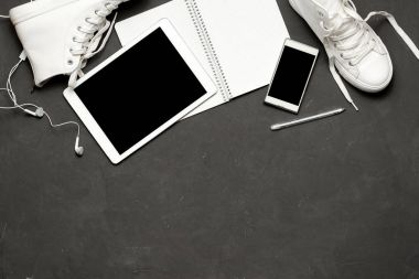Düz yatıyordu, beyaz spor ayakkabı siyah arka plan ile telefon, kulaklık, tablet, kopya kitap