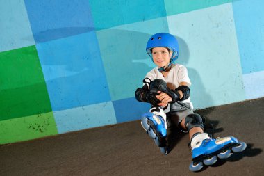 Sevimli küçük atletik çocuk mavi grafiti duvara oturan silindir üzerinde