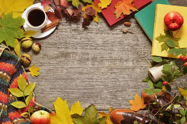 Flat lay frame of autumn red, green and yellow leaves, acorns and apples on a vintage wooden background.