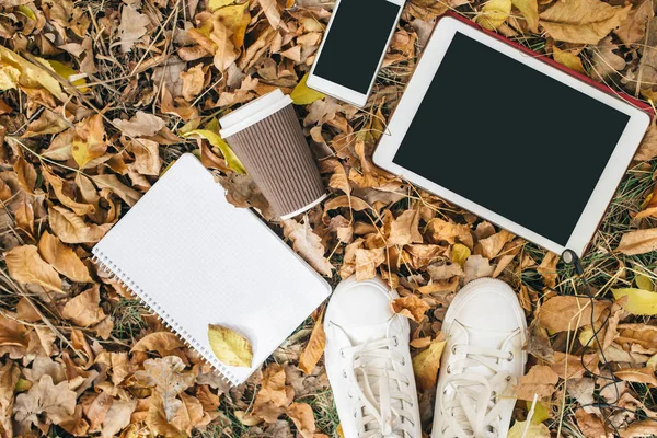 Plat lag weergave van Herfstbladeren, tablet, telefoon en papieren kopje koffie. Van bovenaf met benen — Stockfoto