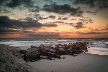 Early morning clouds scud across the horizon above a granite jetty at Holgate, NJ clipart