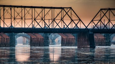 Güneş, kışın Harrisburg, Pennsylvania 'daki Susquehanna Nehri üzerindeki bir dizi köprünün altında parlıyor.