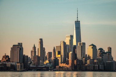 Güneş bir bahar sabahı Hudson nehrinin New Jersey tarafından görüldüğü gibi Manhattan 'ın finans bölgesinde yükseliyor.