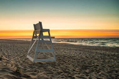 Şafak vakti renkli bir gökyüzü ve Long Beach Adası 'nda boş bir cankurtaran standı olan ıssız bir sahil.