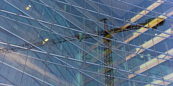 Reflection of construction crane in a modern glass building.