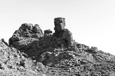 Taş dev bir yol İzlanda'dağ kayaların üzerinden korur. Siyah ve beyaz fotoğraf kayalık bir volkanik arazinin.  