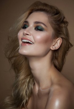 Sarı saç ve parlak yeşil makyaj kadınla. yakın çekim portre bej renkli arka plan üzerinde. parlak ıslak deri