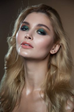 Sarı saç ve parlak yeşil makyaj kadınla. yakın çekim portre bej renkli arka plan üzerinde. parlak ıslak deri