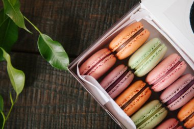 renkli macaroons bir kutu içinde. ahşap arka plan bitki ile lezzetli kurabiyeleri yakın:.