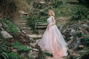 parkta erken ilkbaharda. Beyaz güzel yemyeşil elbiseli kız. sarışın model akşam saç modeli ve etkileyici makyaj ile. Kız merdivenlerde. peyzaj tasarımı