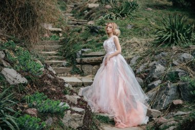 parkta erken ilkbaharda. Beyaz güzel yemyeşil elbiseli kız. sarışın model akşam saç modeli ve etkileyici makyaj ile. Kız merdivenlerde. peyzaj tasarımı