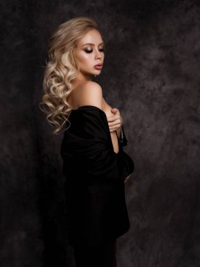 young beautiful woman posing in black pantsuit. model with bright make-up and volume curly hairstyle. fashion portrait.