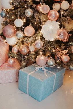 Ağacın altındaki güzel mavi ve pembe kutularda bir sürü yeni yıl hediyesi. Süslü Noel ağacının altında pastel renklerle paketlenmiş hediyeler. Yılbaşı tatilinin hafif fotoğrafı 