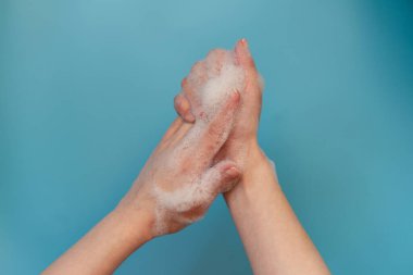 Kadın mavi arka planda izole edilmiş sabun ve el yıkama kullanıyor. Hijyen konsepti el detayı. el hijyeni ellerini sıcak suda sabunla yıkıyor. Koronavirüs mikropları koruma yayıyor..
