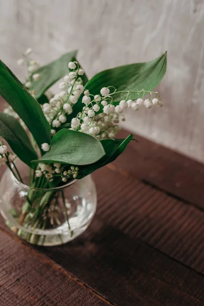 Lilies of the valley closeup. Bouquet of the lily of the valley in glass vase. water drops on the leaves. fragrant Lily-of-the-valley flowers