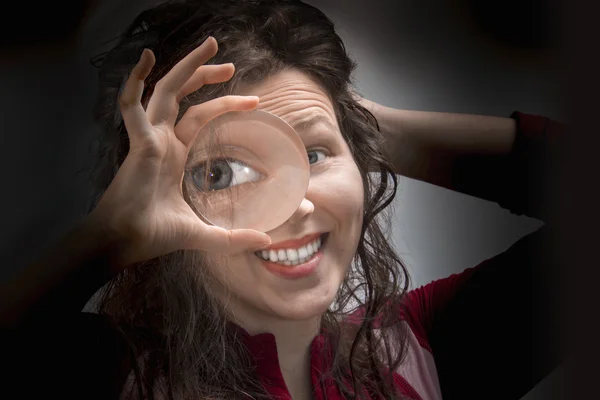Vrouwelijke ogen op zoek via Vergrootglas close-up — Stockfoto