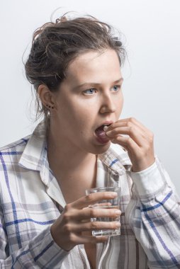 Bir tablet ve bir bardak su onun elinde olan kadın