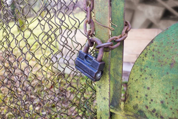 Rostiga gamla hänglås och kätting på en gröna staket — Stockfoto